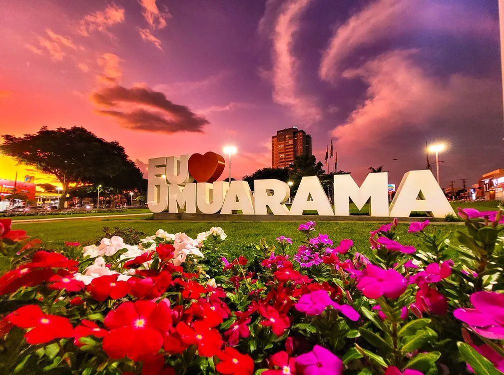Letreiro Eu amo Umuarama cercado por flores ao entardecer